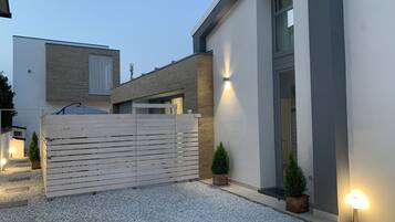 Ein modernes Haus mit einem Schotterweg, einem Holzzaun und zwei Blumentöpfen.