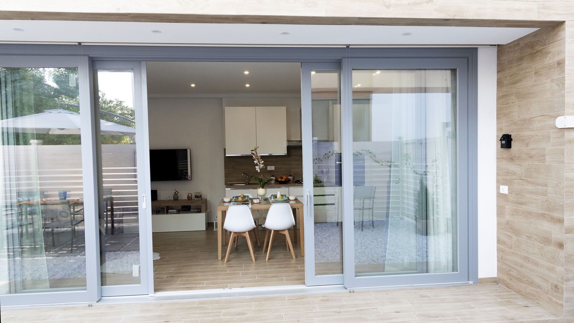A modern kitchen with a dining area, sliding glass doors, and a wooden floor.