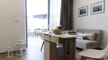 A modern living room with a dining area, a sofa, and a table set with fruits and a bowl.