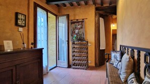 A hallway with a wooden bench, a rack of wine glasses, and a door leading to another room.