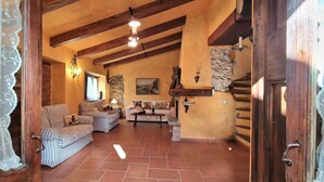 A cozy living room with striped sofas, a stone fireplace, and exposed wooden beams.