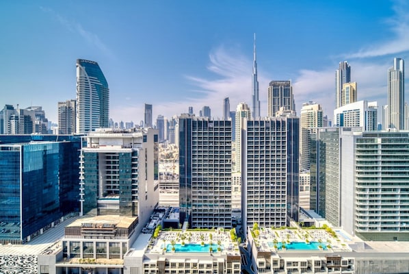 Un hôtel de grande hauteur doté d’une piscine sur le toit, entouré de gratte-ciel modernes.