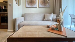 A modern living room with a sofa, a coffee table, and two abstract paintings on the wall. - Modern City Scaping Apartment (Dubai)