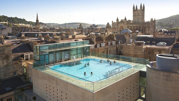 Una piscina en la azotea con vistas despejadas a edificios históricos y una iglesia al fondo.