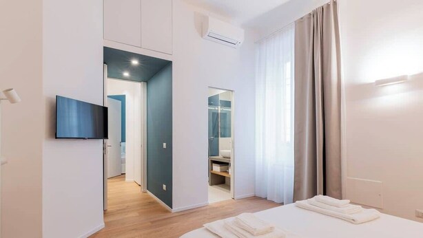 Une chambre d’hôtel moderne dotée d’un grand lit, d’un téléviseur à écran plat fixé au mur et d’un dressing.