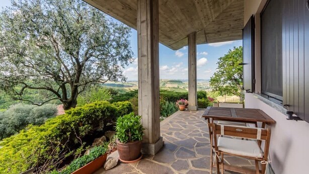 A covered patio with a stone floor, a wooden table and chair, and potted plants. - Panorama villa nestled among the vineyards, Langhe (Bricco di Neive)