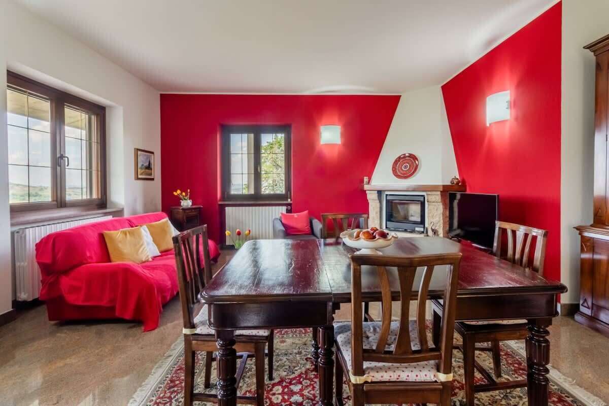 A dining area with a wooden table and chairs, a red sofa, and a fireplace.