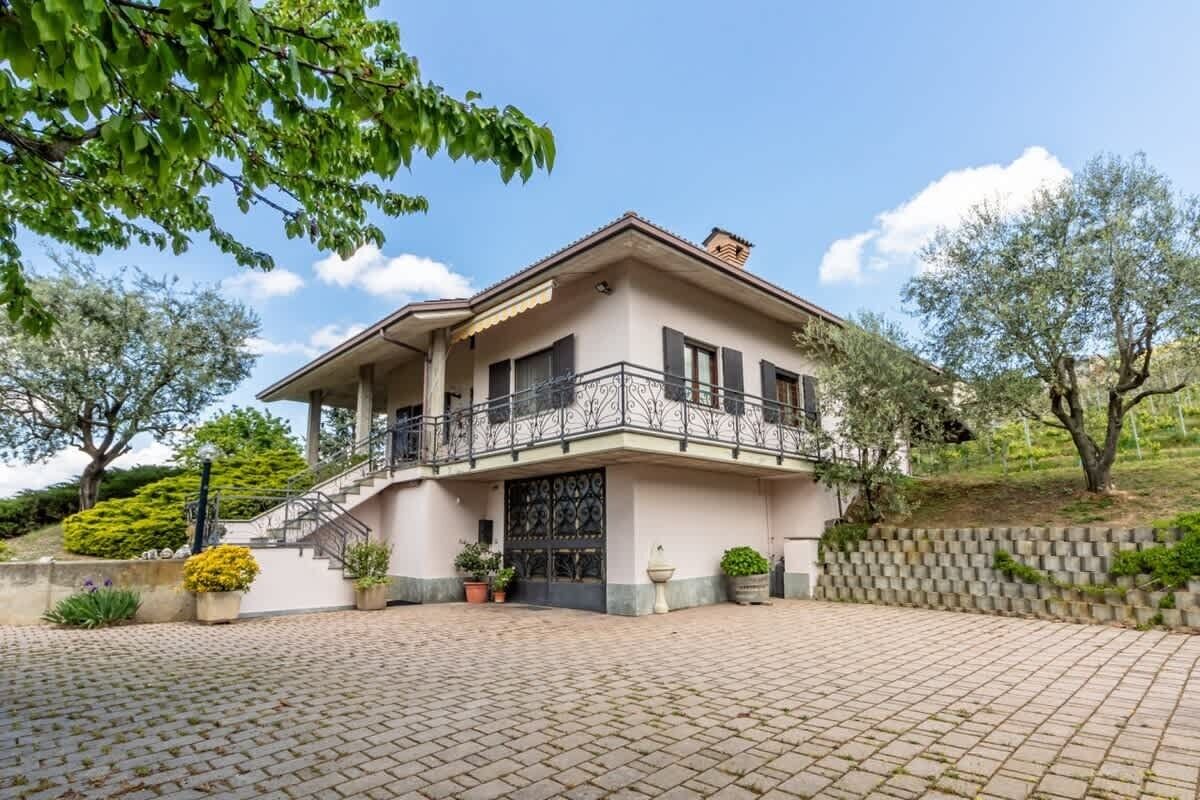 Ein zweistöckiges Haus mit einem Balkon und einer Auffahrt, die zu einem Eingang führt.