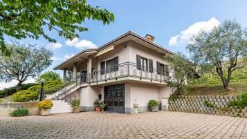 Ein zweistöckiges Haus mit einem Balkon und einer Auffahrt, die zu einem Eingang führt.