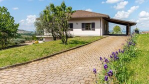 Une maison avec une allée pavée, un porche abrité et une vue sur la campagne.