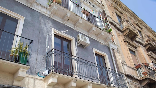 Un edificio a più piani con balconi, condizionatori e una finestra con tenda.