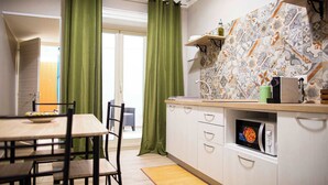 Una cucina moderna con un forno a microonde, un tavolo da pranzo con sedie e una tenda verde.