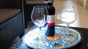 Un tavolo con una bottiglia di vino e due bicchieri su un vassoio decorativo.
