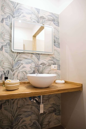 A bathroom with a large white sink, a mirror above it, and a wooden countertop.