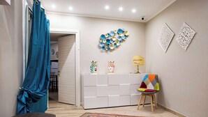 A room with a white cabinet, a colorful chair, a patterned rug, and decorative wall art. - Charming Studio Verga, by the old town (Catania)