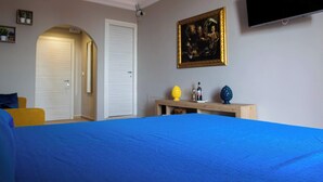 A bedroom with a bed, a TV, a painting, and a desk with a lamp. - Charming Studio Verga, by the old town (Catania)
