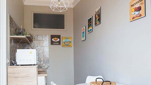 A compact kitchen with a microwave, a small refrigerator, and a dining area with a round table and four chairs. - Charming Studio Verga, by the old town (Catania)