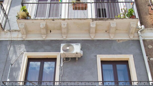 A multi-story building with balconies, air conditioning units, and a window with a red curtain. - Charming Studio Verga, by the old town (Catania)