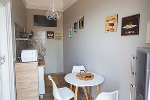 A compact kitchen with a microwave, a small dining table with chairs, and a refrigerator. - Charming Studio Verga, by the old town (Catania)