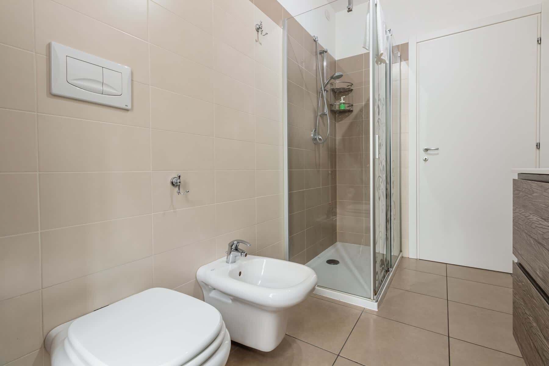 Un bagno con toilette, bidet e cabina doccia in vetro.