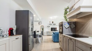 A modern kitchen with a refrigerator, stove, and dining area. - Casa Barbara, modern and peaceful with balcony (Milano)