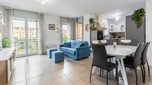 A modern apartment with a dining area, a blue sofa, and a kitchen. - Casa Barbara, modern and peaceful with balcony (Milano)