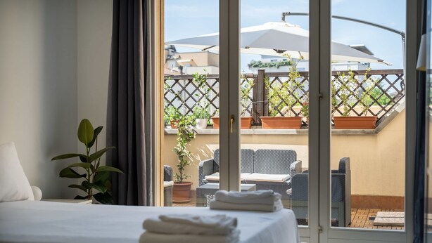 A hotel room with a bed, a potted plant, and a view of the outdoor seating area. - Savena Terrace Apartment, in the heart of San Lazzaro (San Lazzaro di Savena)