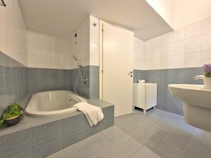 Un baño moderno con una bañera independiente, un lavamanos y una ducha.