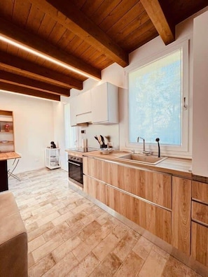 A modern kitchen with wooden cabinets, a large window, and a herringbone-patterned floor.