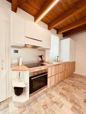 A modern kitchen with white cabinetry, a wooden countertop, and a herringbone-patterned floor.