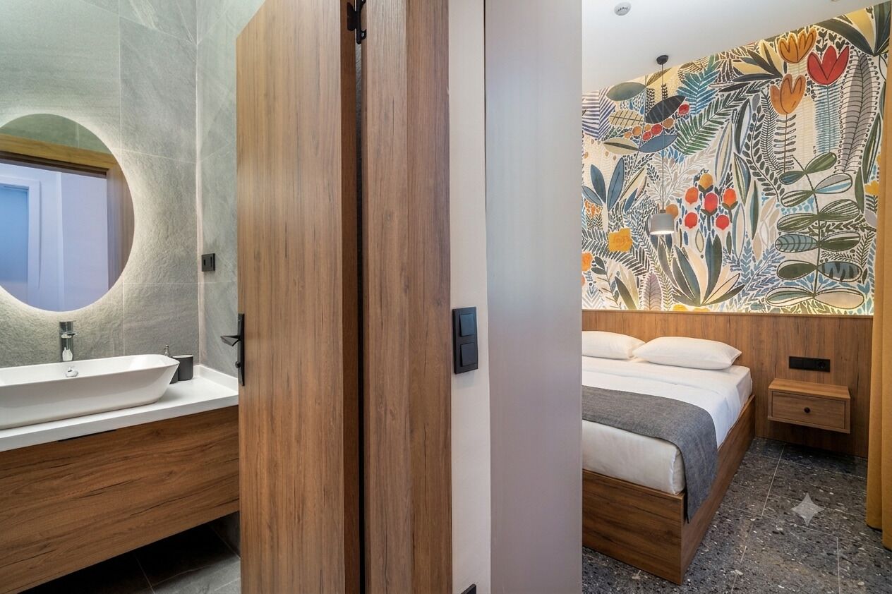 A modern bathroom with a wooden vanity, a round mirror, and a large sink.