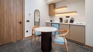 Une cuisine compacte avec une table ronde, deux chaises, une machine à café et un four encastré.