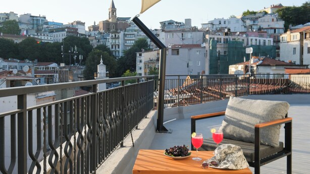 Un balcon avec une table, une chaise et une boisson.