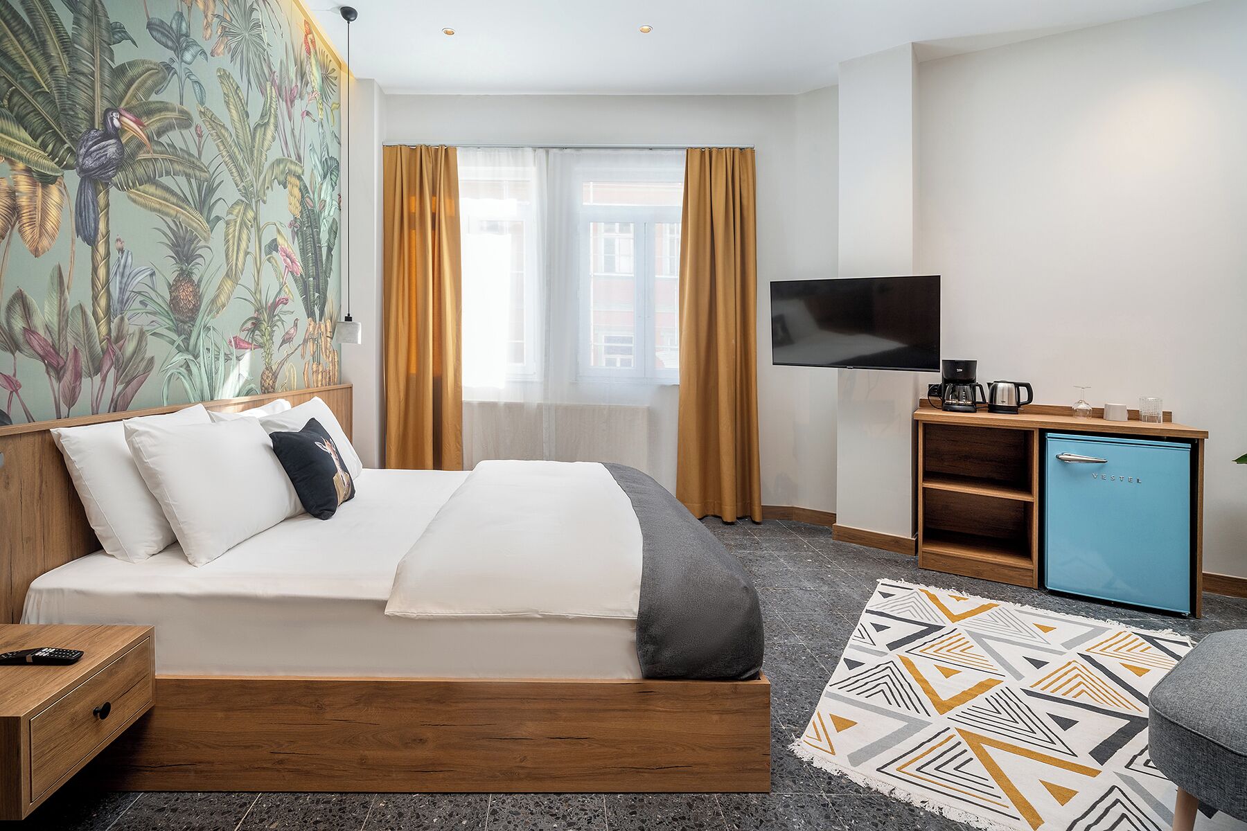A hotel room with a bed, a TV, a coffee maker, and a minibar.