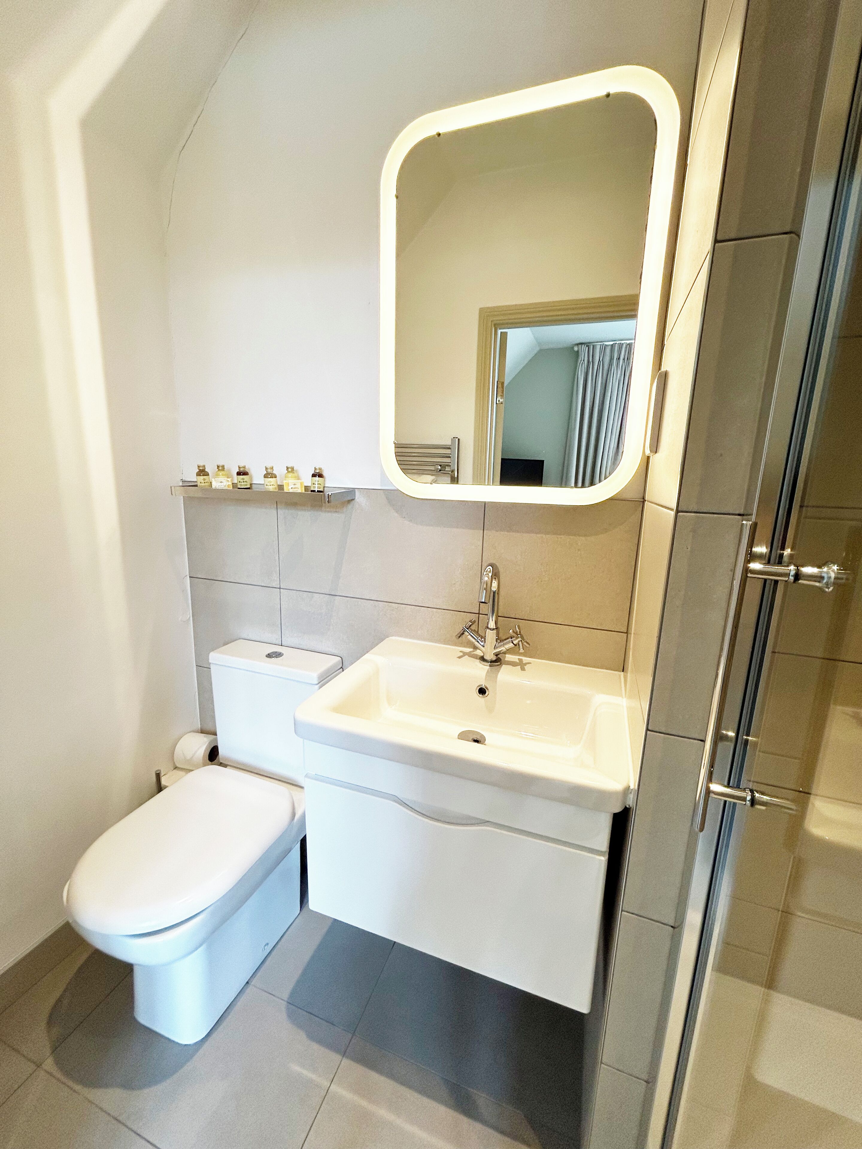 A bathroom with a toilet, sink, and mirror.