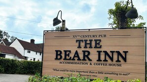 Un letrero de madera anuncia The Bear Inn, un pub del siglo XV, con alojamiento y una casa de café, e incluye una cita de Winnie the Pooh.