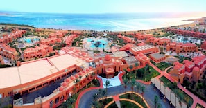 Un complexe hôtelier doté de plusieurs piscines, de palmiers et offrant une vue sur la plage.