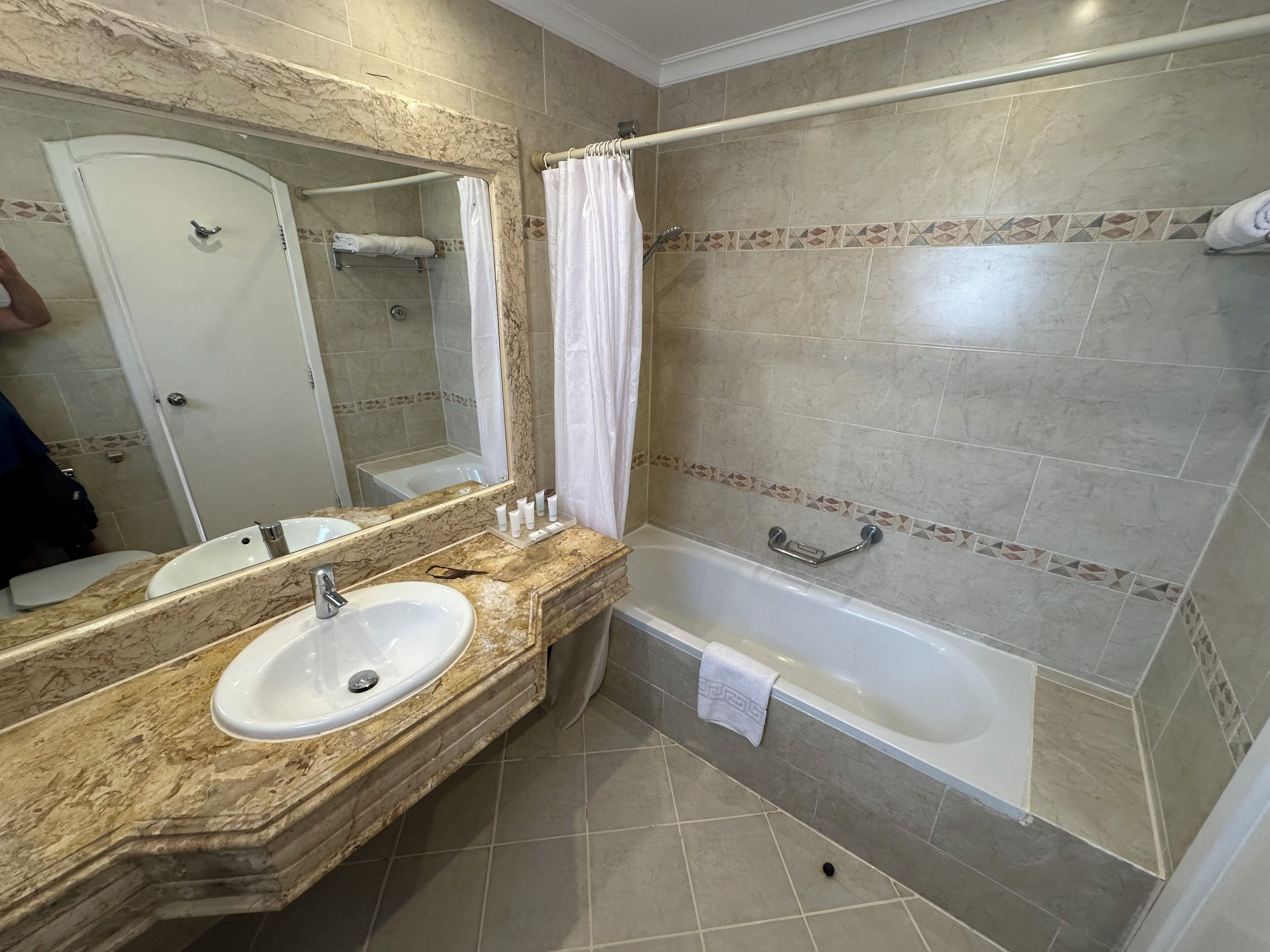 A bathroom with a marble sink, a bathtub, and a shower curtain.
