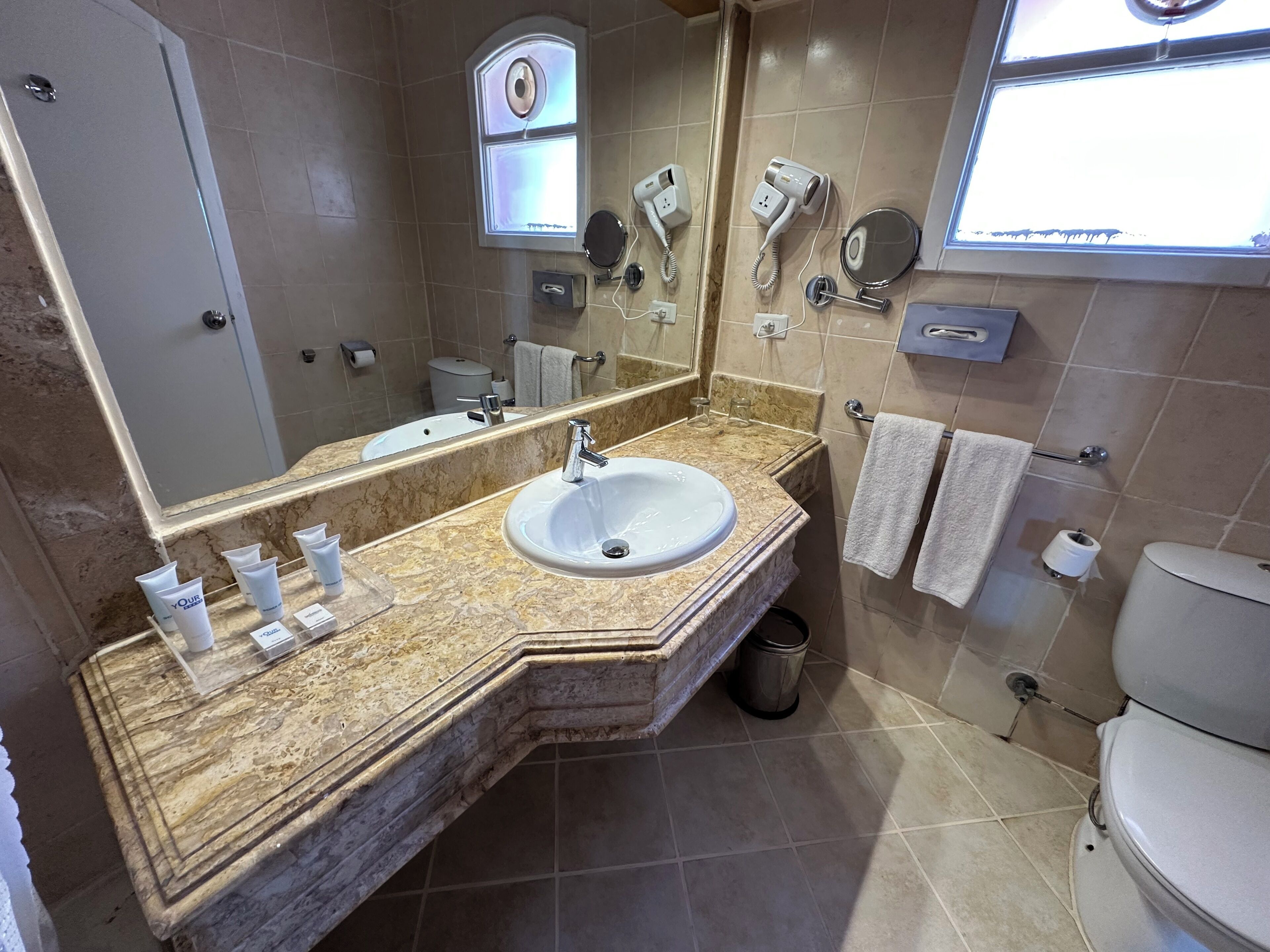 Une salle de bain équipée d’un lavabo, d’un miroir, d’un porte-serviettes et d’un sèche-cheveux.
