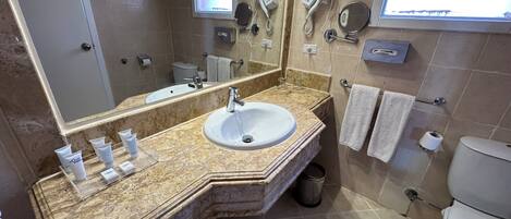 Une salle de bain équipée d’un lavabo, d’un miroir, d’un porte-serviettes et d’un sèche-cheveux.