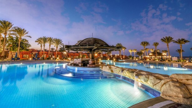 A large outdoor swimming pool with a central water feature and a covered seating area. - Swisstouch Oriental Resort Marsa Alam - All inclusive (El Quseir)