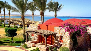 A resort with palm trees, a pool, and red-roofed buildings. - Swisstouch Oriental Resort Marsa Alam - All inclusive (El Quseir)