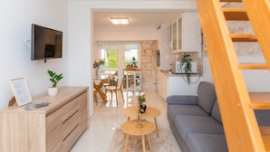 A modern living room with a flat-screen TV, wooden furniture, a staircase, and a dining area with natural light. - Apartments Tino (Sutivan)
