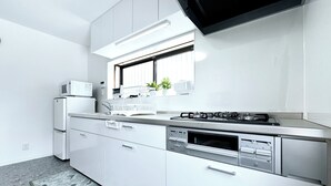 Une cuisine moderne avec des meubles blancs, un four à micro-ondes encastré, une cuisinière à gaz et un lave-vaisselle.