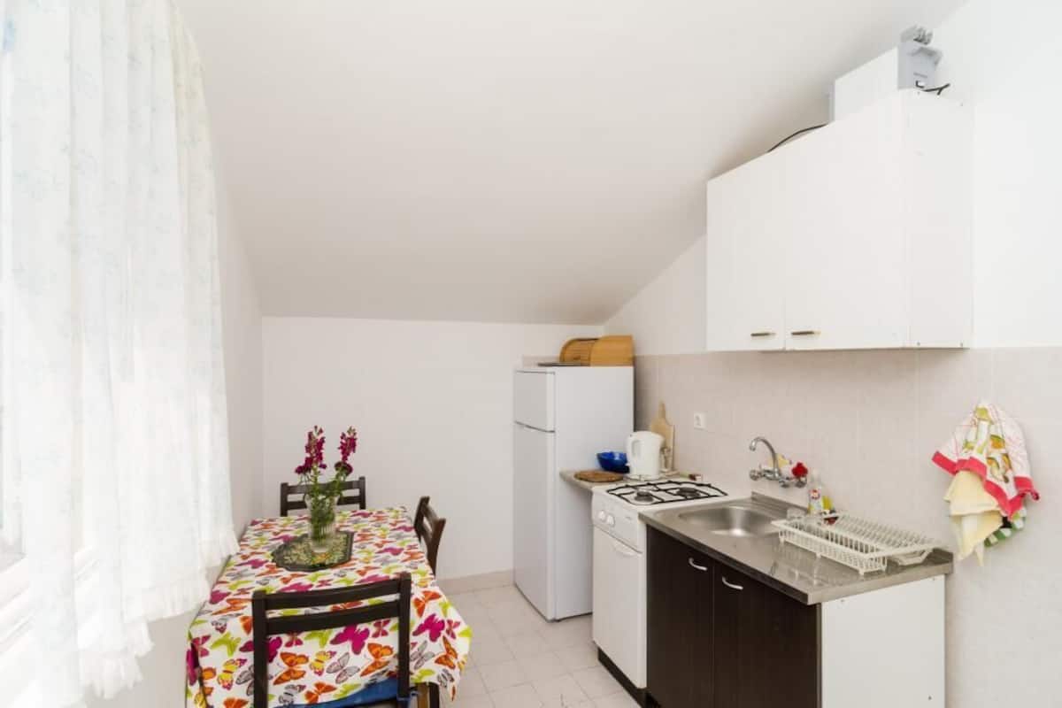 A small kitchen with a dining table, a refrigerator, a stove, and a sink.