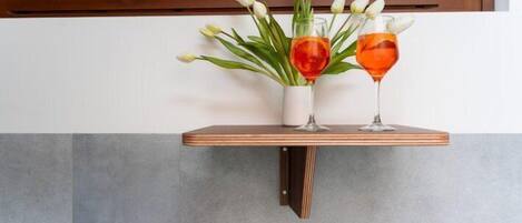 A wooden shelf with a vase of white tulips and two glasses of red wine.