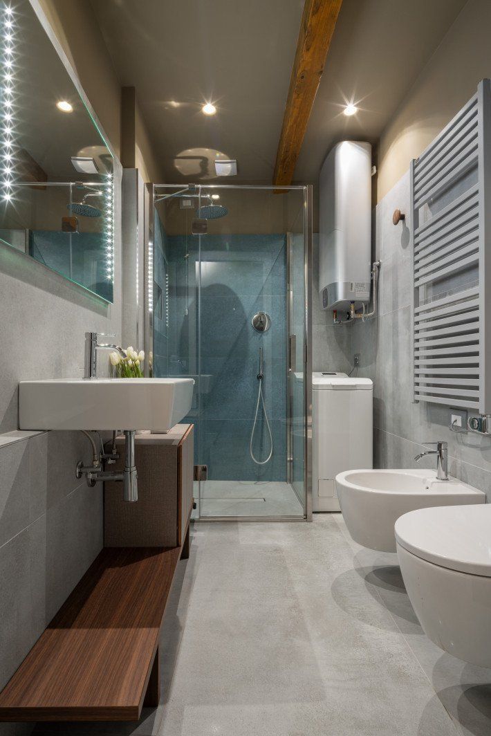 A modern bathroom with a glass-enclosed shower, two sinks, and a wooden bench.