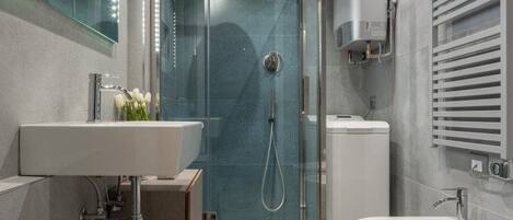 A modern bathroom with a glass-enclosed shower, two sinks, and a wooden bench.