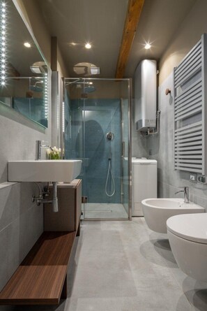 A modern bathroom with a glass-enclosed shower, two sinks, and a wooden bench. - Venice Jewel Canal View by Wonderful Italy (Venice)