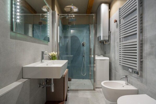 A modern bathroom with a glass-enclosed shower, a vanity with a sink, and a separate pedestal sink. - Venice Jewel Canal View by Wonderful Italy (Venice)